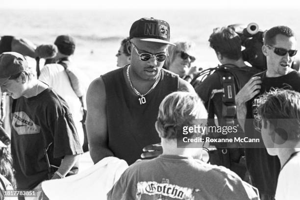 Tim Hardaway of the Golden State Warriors wears a number 10 necklace, sunglasses, a Nike hat and a tank top while he signs autographs for young fans...