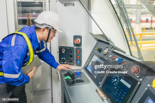 engineer overall checking in driving control system in driver cabin of the electric train with digital laptop for engineering industry or transportation concept. - machinist stockfoto's en -beelden
