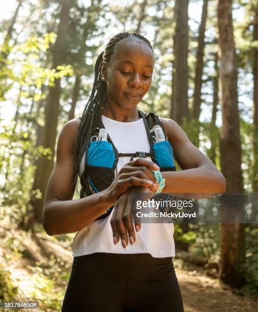 woman runner checking results on smart watch after training in forest - self discipline imagens e fotografias de stock