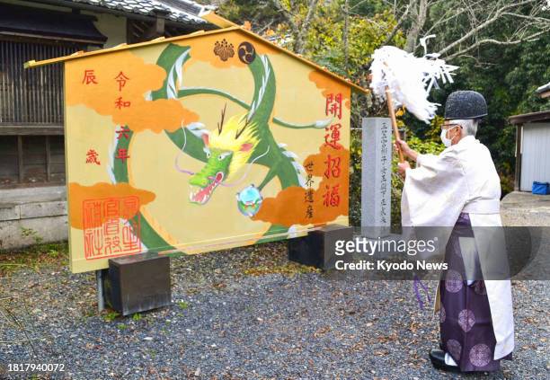 Chief priest performs a purification ritual in front of a giant "ema" prayer plaque with an illustration of a dragon, the Chinese zodiac sign for...