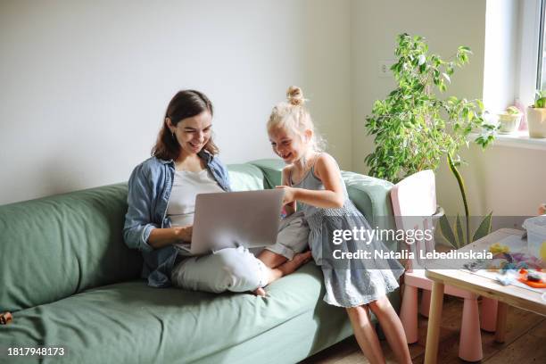 cozy maternal work: emotional mom pregnant, working on green couch with sibling children. - children screen stock-fotos und bilder