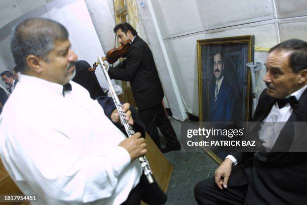 Members of Iraq's 45-musician National Philharmonic Orchestra rehearse backstage, next to a portrait of President Saddam Hussein, prior to a concert...