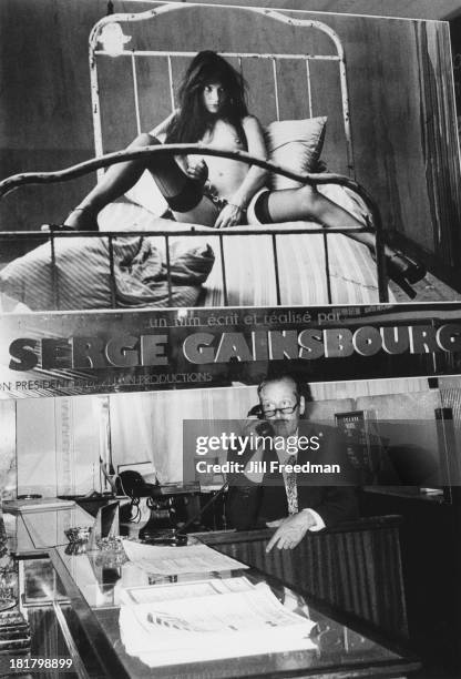 Receptionist on the front desk of a hotel sits beneath a poster showing Serge Gainsbourg's photograph of Jane Birkin taken for 'Lui' magazine during...