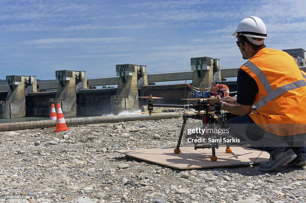 Pilot preparing a drone with camera to film a dam