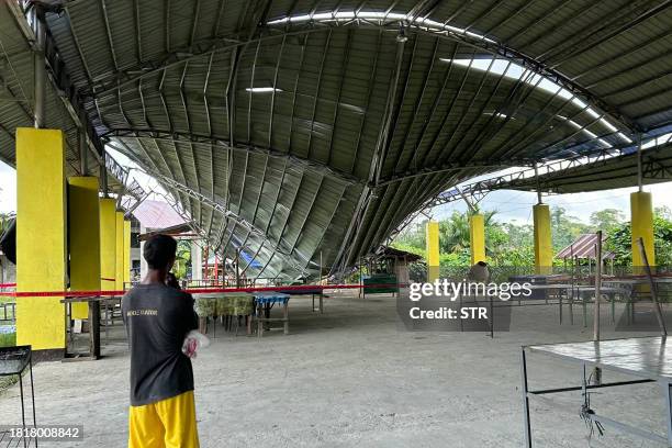 Person looks at the collapsed roof of a building following a 7.6 magnitude earthquake in Tagbina, Surigao del Sur province on December 3, 2023. At...