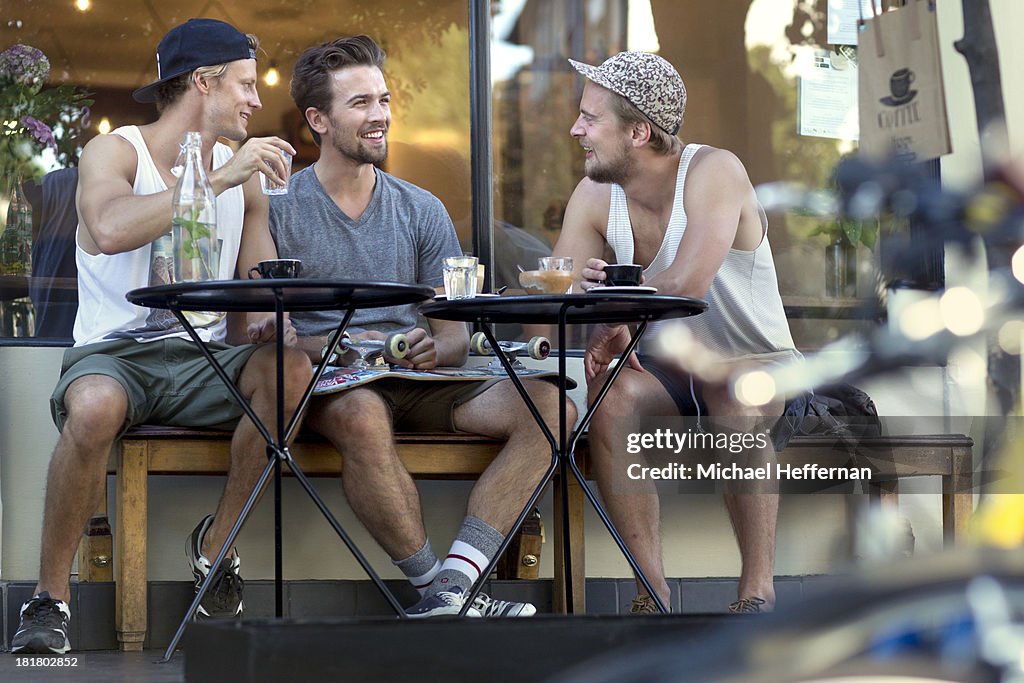 Three young men sitting outside cafe