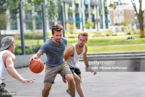 three young men playing basketball - nur junge männer stock-fotos und bilder