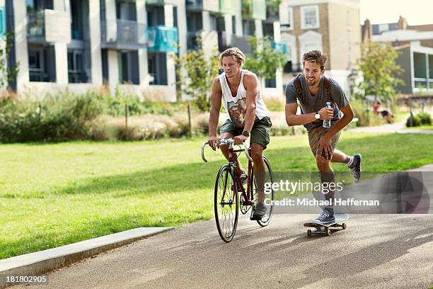 male cyclist and skateboarder in park - cycling shorts stock-fotos und bilder