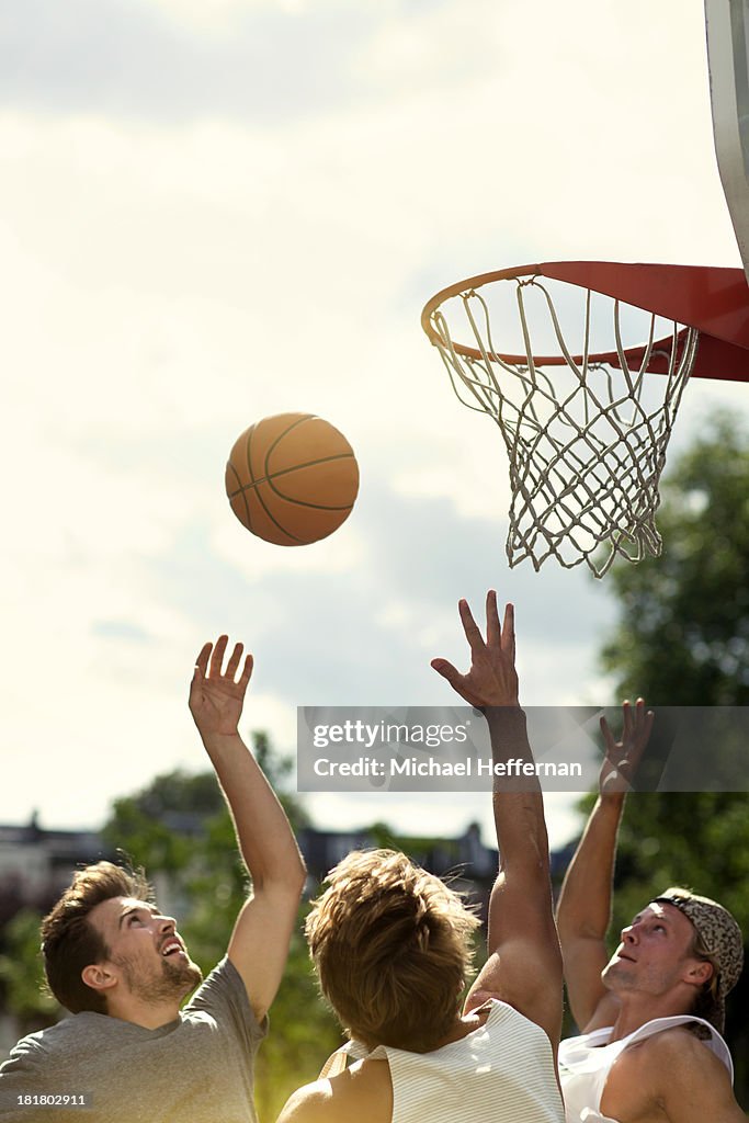 Three young men playing basketball