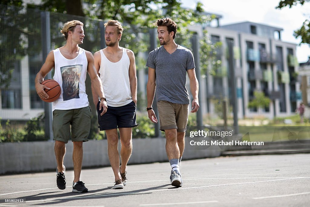 Three young men walk on basketball court