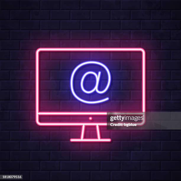 desktop computer with at symbol. glowing neon icon on brick wall background - at symbol stock illustrations