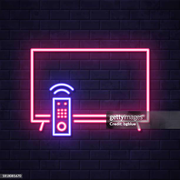 tv and remote control. glowing neon icon on brick wall background - flat tv wall stock illustrations