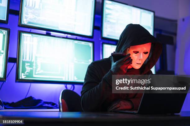 hacker wearing mask using laptop computer for cyber attack and calling on cellphone, data thief, internet attack, darknet and cyber security concept - scammer trickbetrüger stock-fotos und bilder