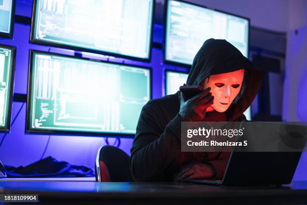 hacker wearing mask using laptop computer for cyber attack and calling on cellphone, data thief, internet attack, darknet and cyber security concept - anonymous mask photos et images de collection