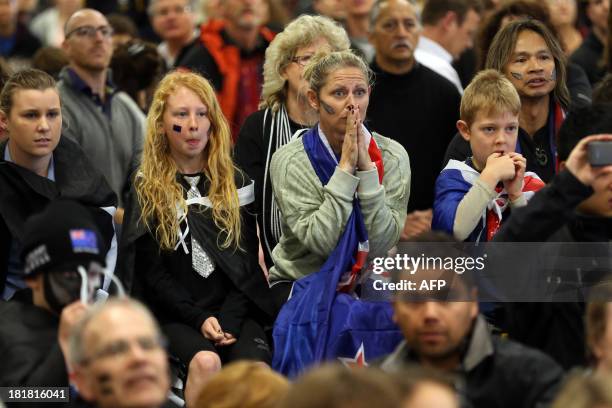 Fans of Team New Zealand react as they watch racing in the America's Cup at a venue set up in downtown Auckland with large television screens on...