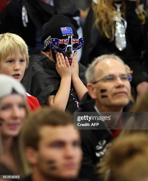 Fans of Team New Zealand react as they watch racing in the America's Cup at a venue set up in downtown Auckland with large television screens on...