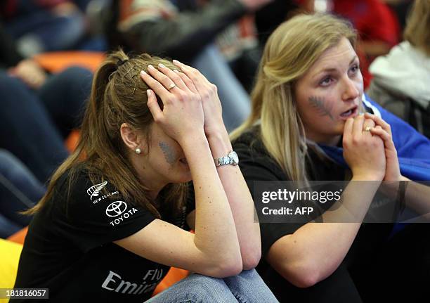 Fans of Team New Zealand react as they watch racing in the America's Cup at a venue set up in downtown Auckland with large television screens on...