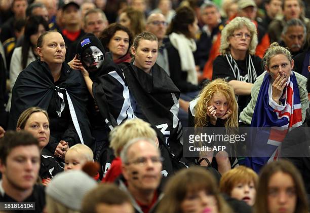 Fans of Team New Zealand react as they watch racing in the America's Cup at a venue set up in downtown Auckland with large television screens on...