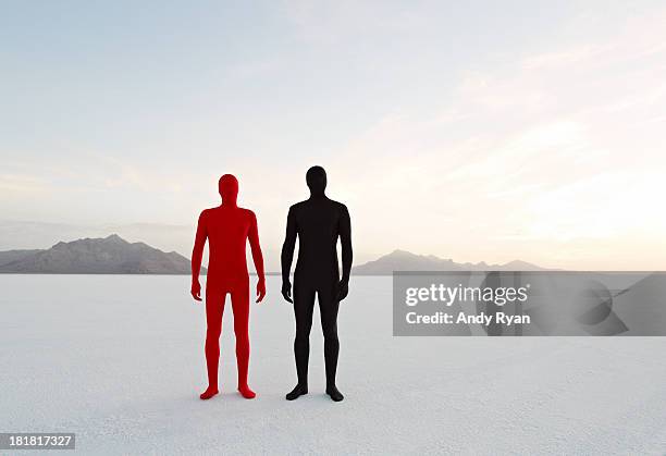 two men in bodysuits stand in desert. - bodysuit stock-fotos und bilder