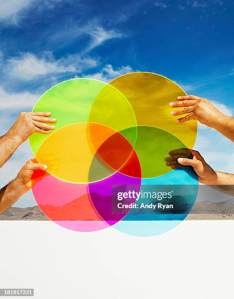 hands holding multi-colored discs in landscape. - multi coloured choice stock pictures, royalty-free photos & images