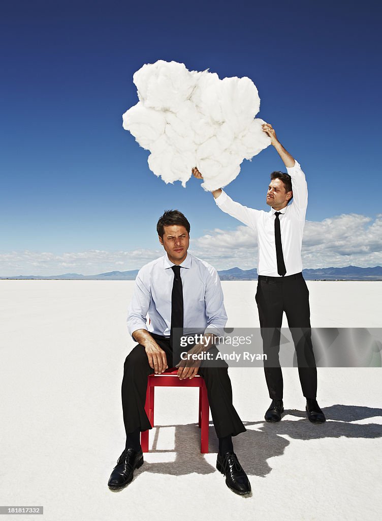 Man holding cloud over another man's head.
