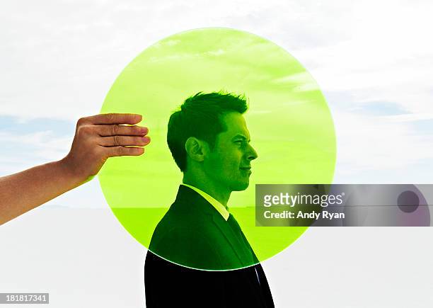 hand holding green circle in fron of man's head. - environmental stewardship stock pictures, royalty-free photos & images