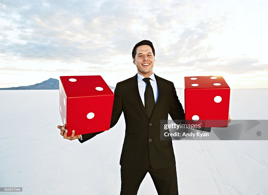 Businessman holding giant dice, smiling.