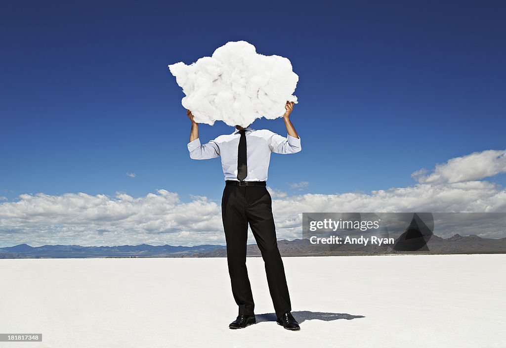 Man holding cloud in front of head in desert.