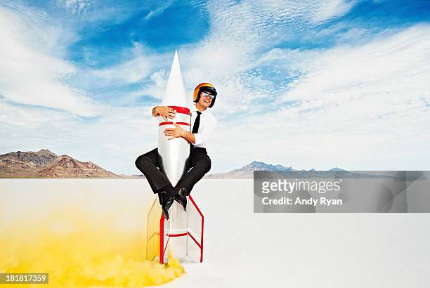 man in helmet astride rocket about to take off. - rakete stock-fotos und bilder
