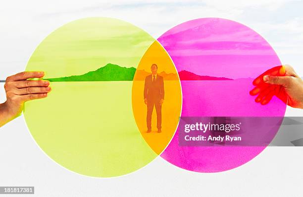 hands holding colored discs, man in background. - entre deux photos et images de collection