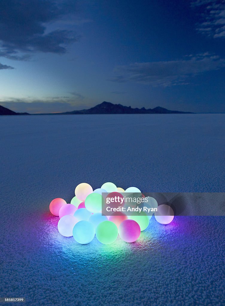 Pile of glowing orbs in desert at dusk.