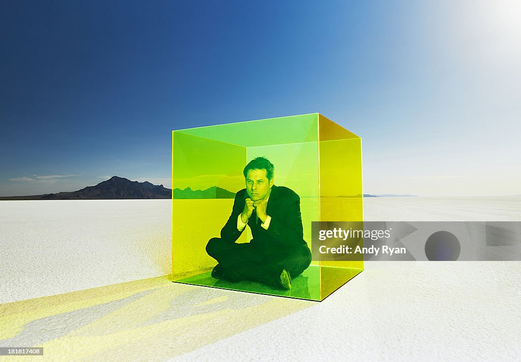 Frustrated businessman in box in desert.