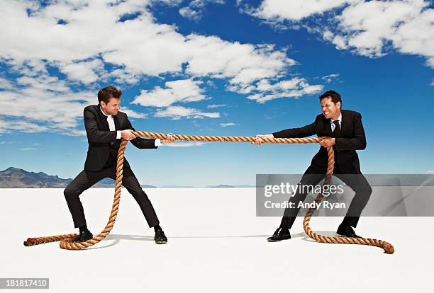 businessmen tug o' war in desert. - tug of war stock pictures, royalty-free photos & images