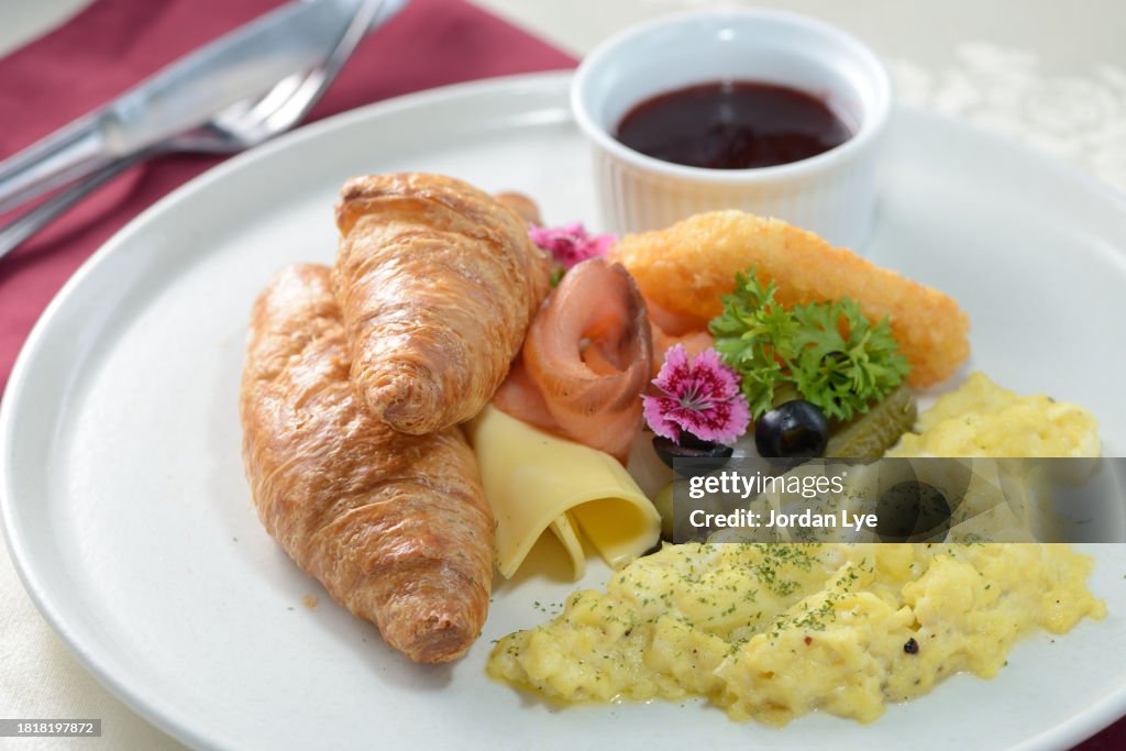 Breakfast with croissant, scrambled eggs, salmon and olive