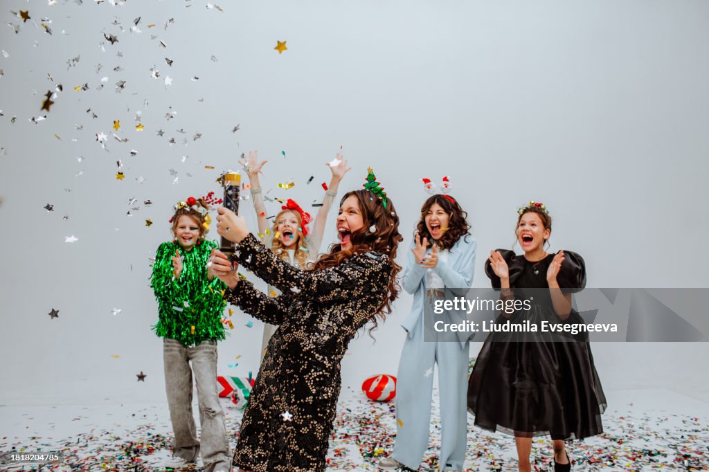 Cute teen girls with hairdressers posing in studio with confetti and balloons.