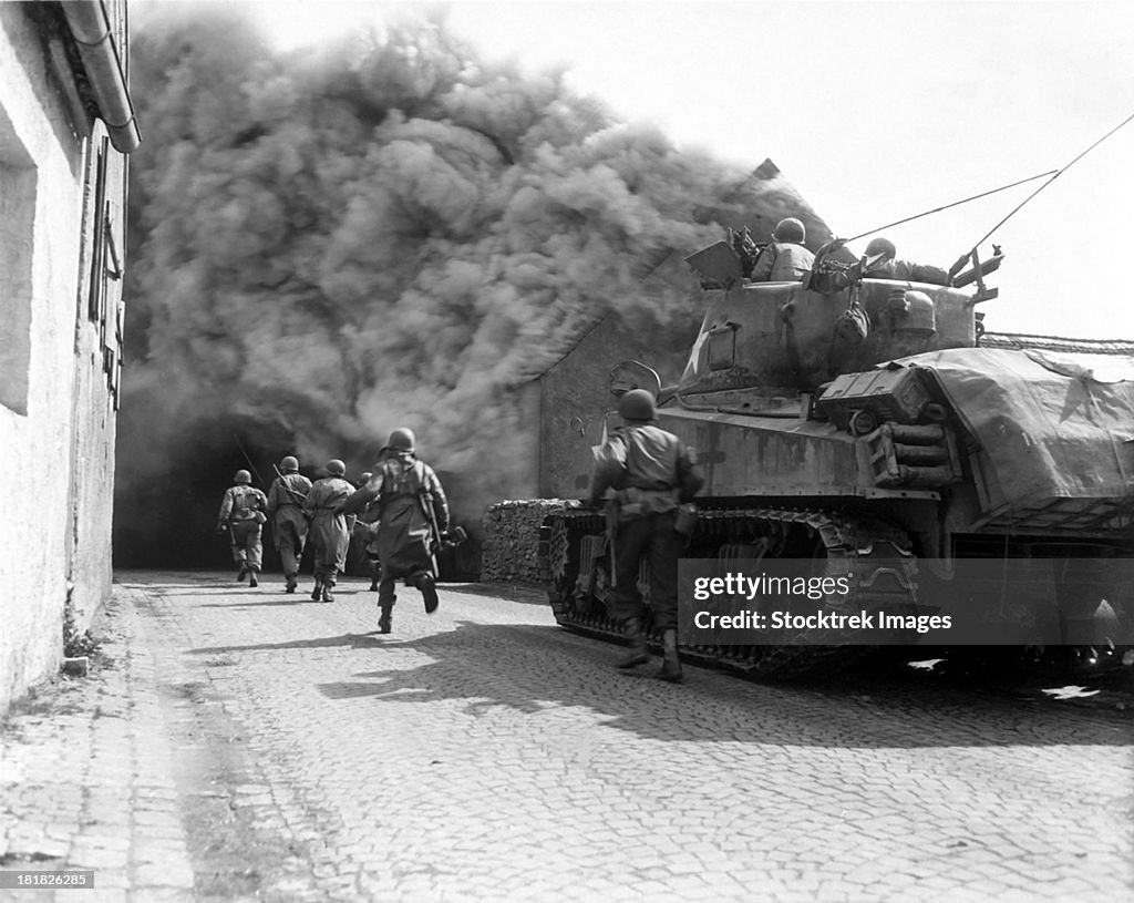 Soldiers move through a smoke filled street, Wernberg, Germany.