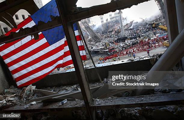 the american flag is prominent amongst the rubble of what was once the world trade center. - 911 new york stockfoto's en -beelden