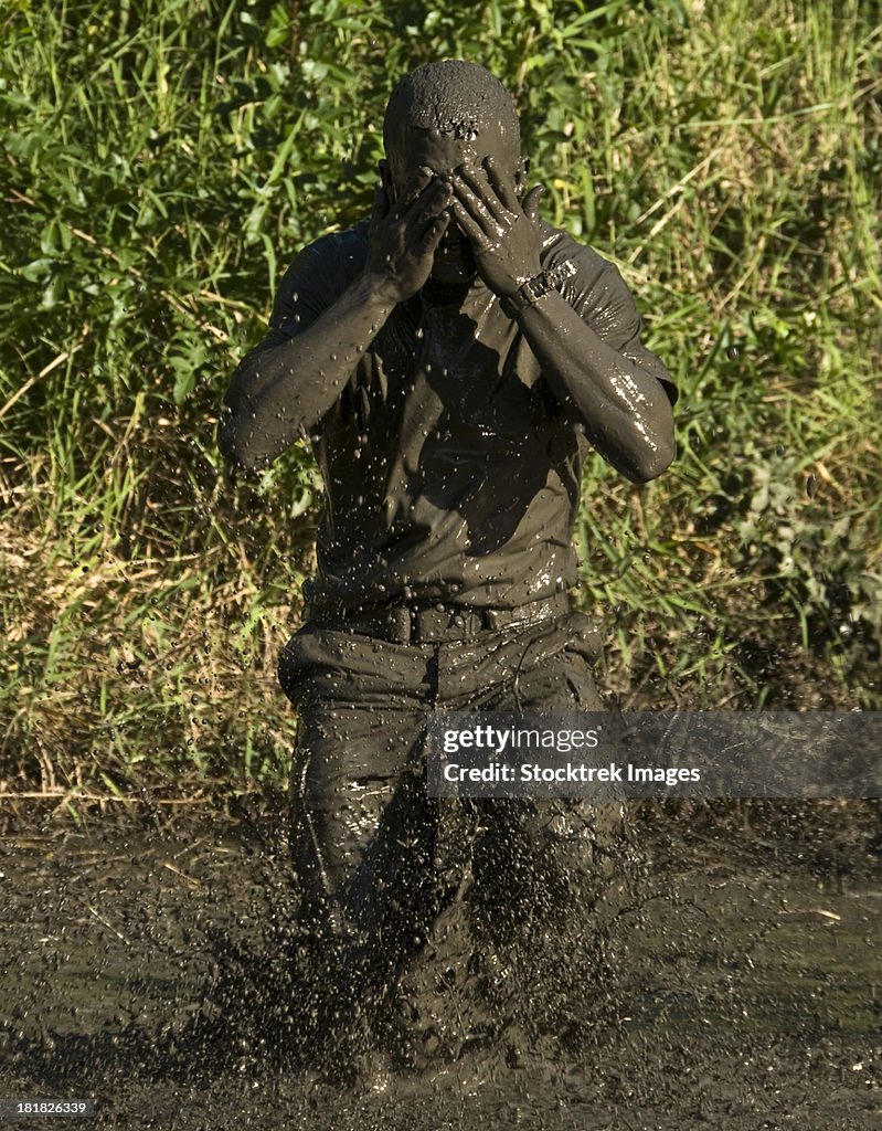 A participant wipes mud from his face after jumping in a pond.