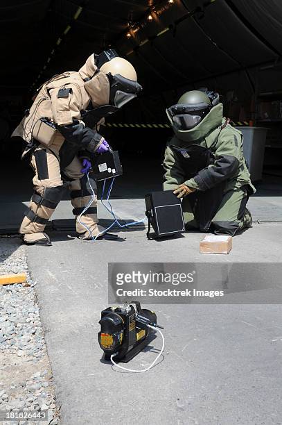 soldiers dressed in bomb suits examine a suspicious package. - suspicious package stock pictures, royalty-free photos & images