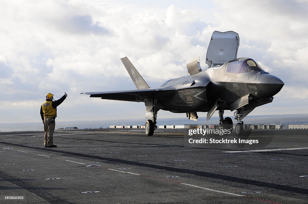 Aviation Boatswain's Mate signals the pilot to lift an F-35B Lightning II off the flight deck.