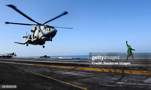 airman directs an eh-101 merlin helicopter onto the flight deck of uss john c. stennis. - operation enduring freedom stock pictures, royalty-free photos & images