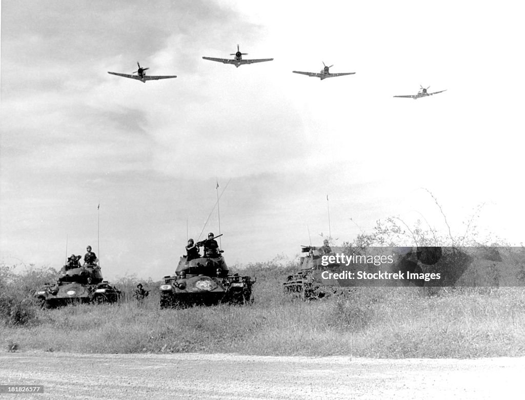 A-1H aircraft make a low level pass over Vietnamese tanks and ground troops.