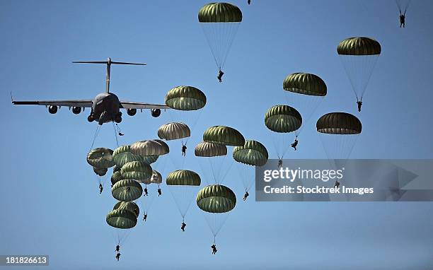 u.s. army paratroopers jumping out of a c-17 globemaster iii aircraft. - fallschirmjäger stock-fotos und bilder