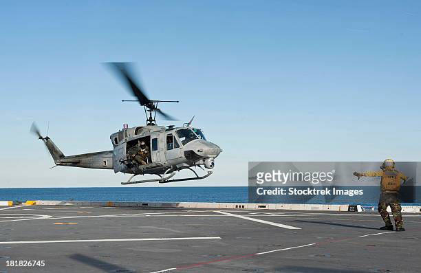 a sailor directs a uh-1n huey helicopter aboard uss new york. - huey helicopter stockfoto's en -beelden