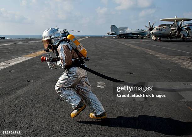 aviation boatswain's mate carries a fire hose during a fire drill. - operation enduring freedom stock pictures, royalty-free photos & images