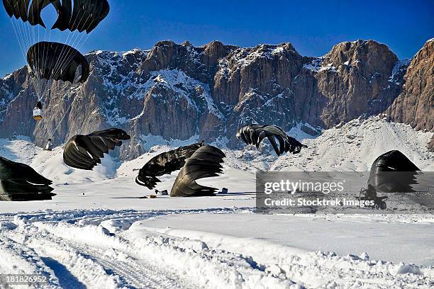 pallets of supplies land in the snow-covered ground during an airdrop in afghanistan. - military crate stock pictures, royalty-free photos & images