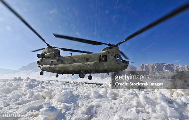 snow flies up as a u.s. army ch-47 chinook helicopter prepares to land. - chinook stock-fotos und bilder
