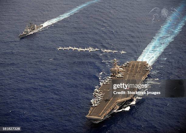 f/a-18 hornets fly in formation over uss abraham lincoln and uss cape st. george. - uss abraham lincoln stockfoto's en -beelden