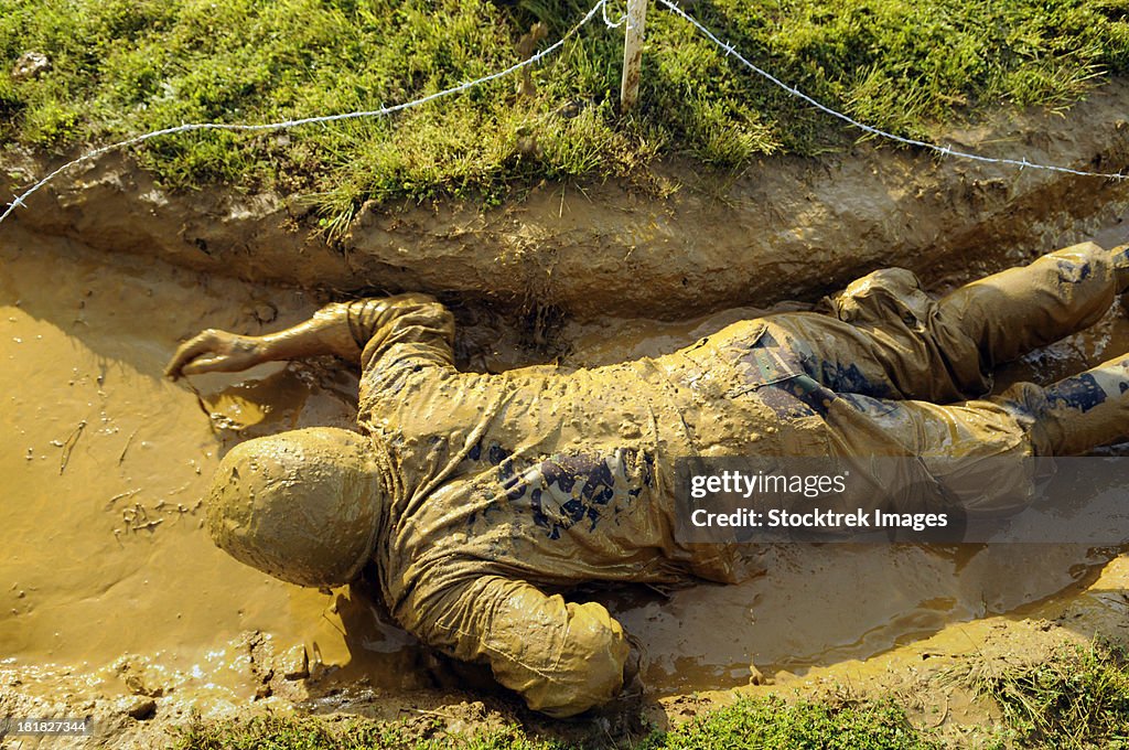 A U.S. Navy midshipman crawls through a foxhole.