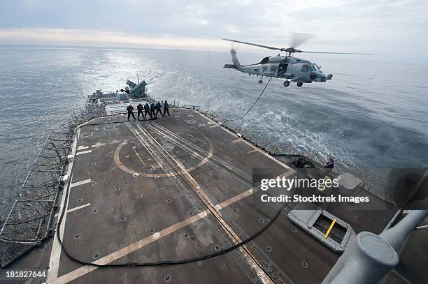 sailors hold a fuel line during a helicopter-in-flight refueling exercise. - aerial refueling stock-fotos und bilder